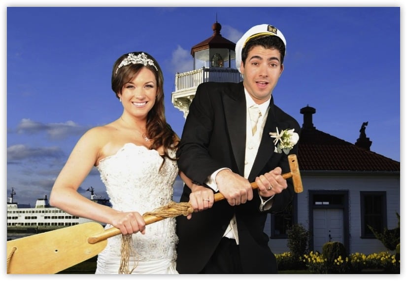 Newlyweds holding an oar in front of a light house