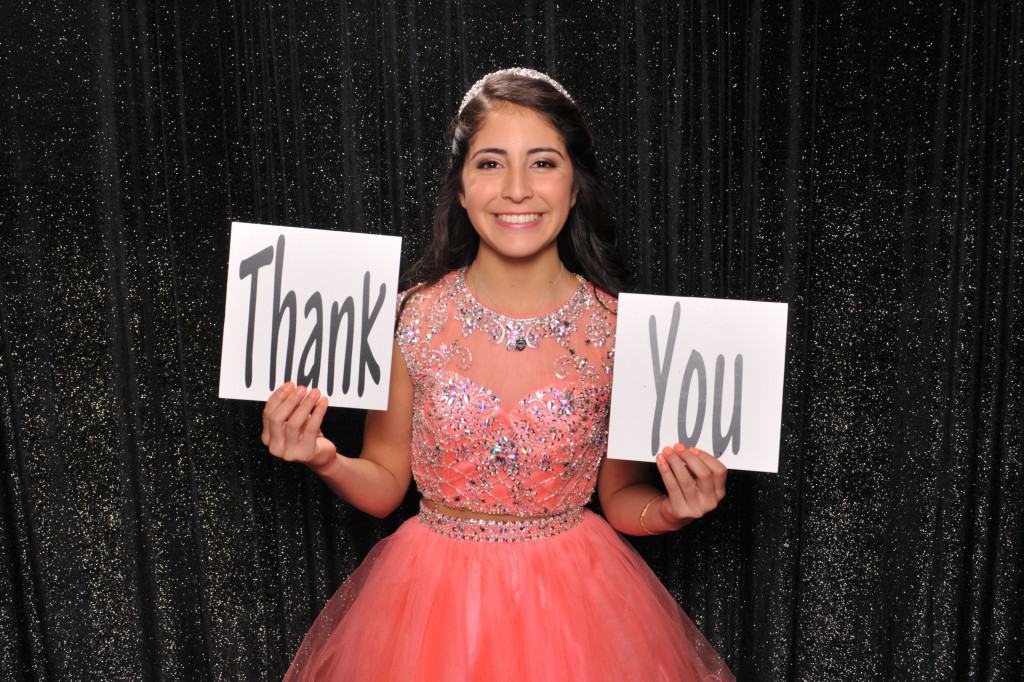 young girl at a Quinceañera holding a thank you sign